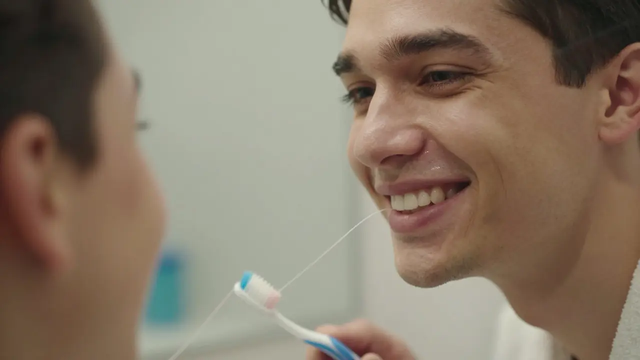 Patient smiling in mirror after successful dental implant treatment.